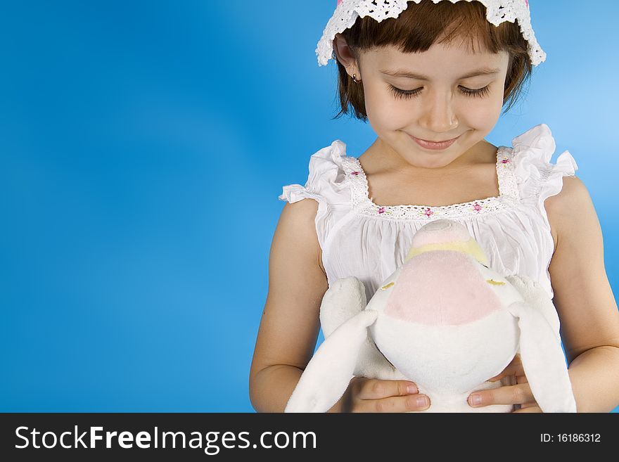 Little girl plays with a soft toy. A blue background. Little girl plays with a soft toy. A blue background.