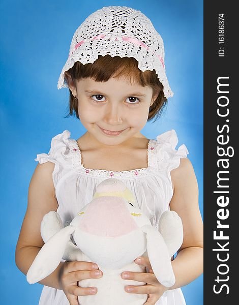 Little girl plays with a soft toy. A blue background. Little girl plays with a soft toy. A blue background.