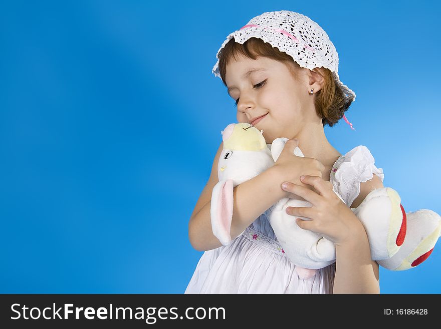 Little girl plays with a soft toy. A blue background. Little girl plays with a soft toy. A blue background.