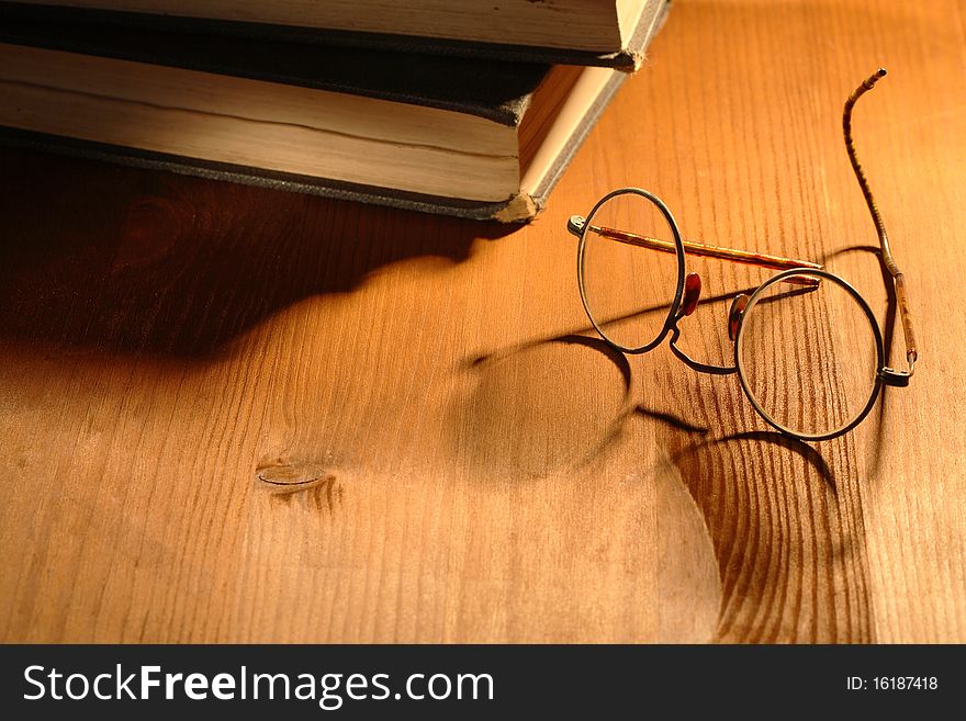 Very old eyeglasses near two books lying on nice wooden background. Very old eyeglasses near two books lying on nice wooden background