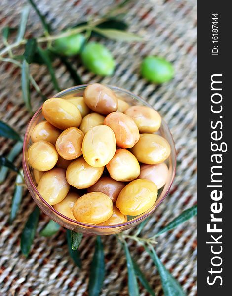 Green olives with leaves on cane background