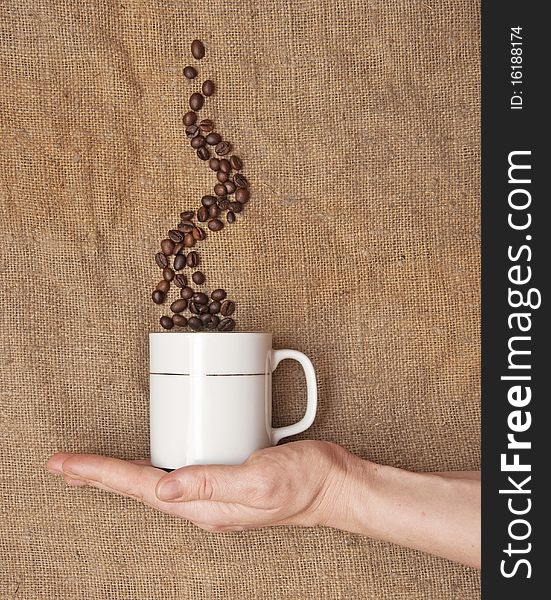 Female hand holding a mug. smoke made of coffee beans