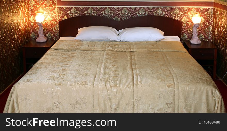 Bed with two pillows and lamps in the room with red wall