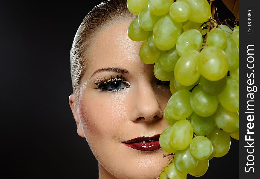 Beautiful woman with bright make-up holding green grapes. Beautiful woman with bright make-up holding green grapes