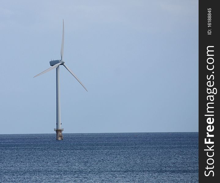 A Single Wind Turbine Tower Standing in the Sea.