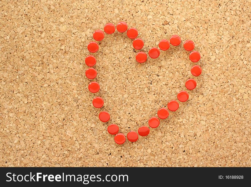 Heart shaped symbol created from red drawing pins on a cork notice board. Heart shaped symbol created from red drawing pins on a cork notice board