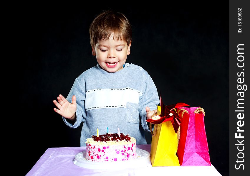 Cute three year old baby celebrating his birthday and blowing off the candles on the cake. Cute three year old baby celebrating his birthday and blowing off the candles on the cake