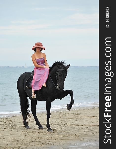 Beautiful black stallion on the beach with young woman. Beautiful black stallion on the beach with young woman