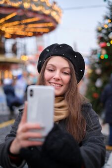 Beautiful Young Woman Taking A Selfie With Christmas Tree Behind Her With Mobile Phone Camera - Pretty Girl Enjoying Royalty Free Stock Photos Beautiful Young Woman Taking A Selfie With Christmas Tree Behind Her With Mobile Phone Camera - Pretty Girl Enjoying Royalty Free Stock Photos