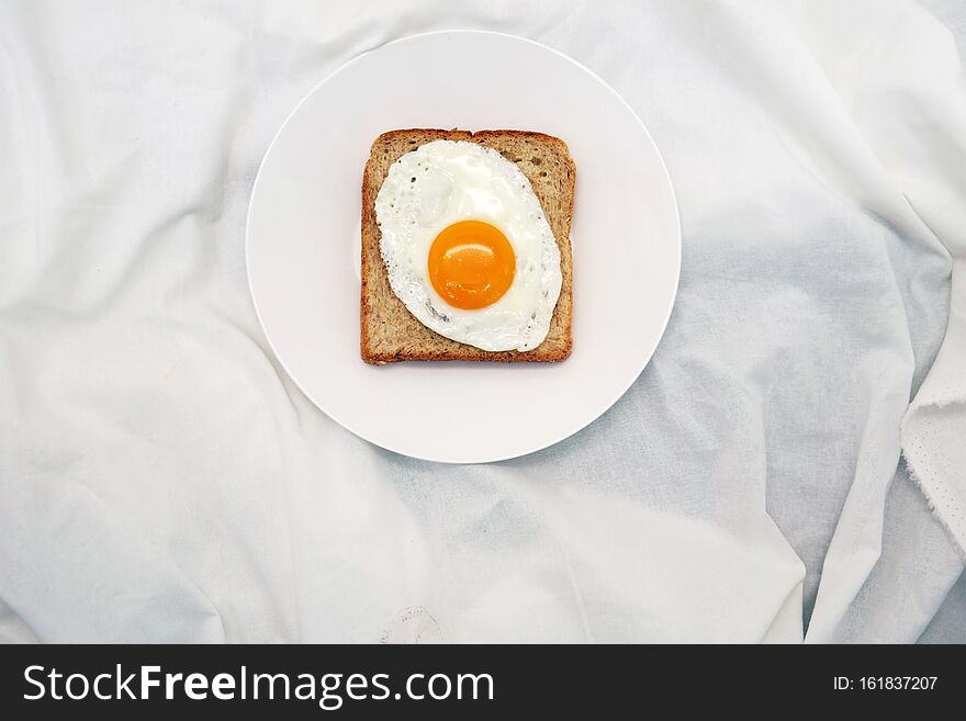 Toasted Bread With Fried Egg On The White Plate Fabric Background. Toasted Bread With Fried Egg On The White Plate Fabric Background