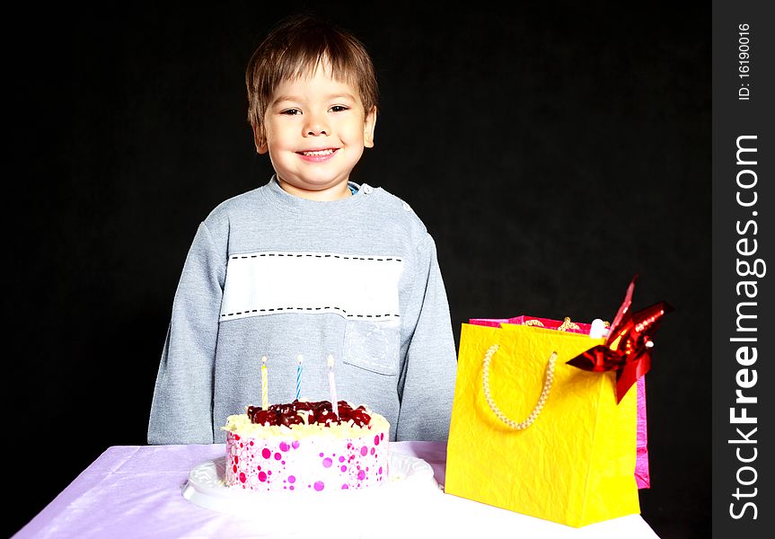 Cute three year old baby celebrating his birthday and blowing off the candles on the cake. Cute three year old baby celebrating his birthday and blowing off the candles on the cake