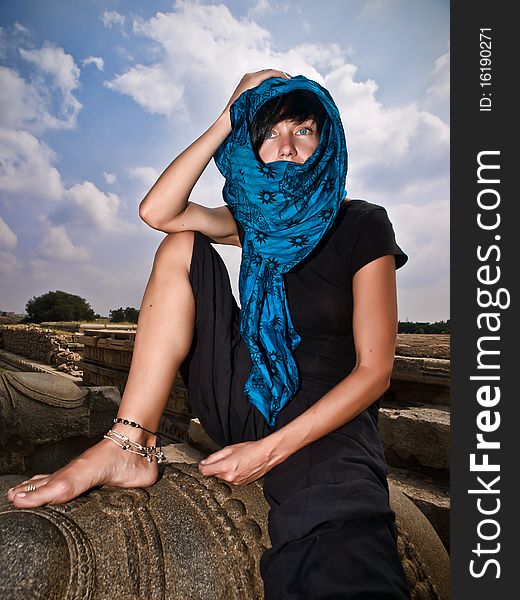 Woman in blue kerchief sits on stone sculpture. Woman in blue kerchief sits on stone sculpture