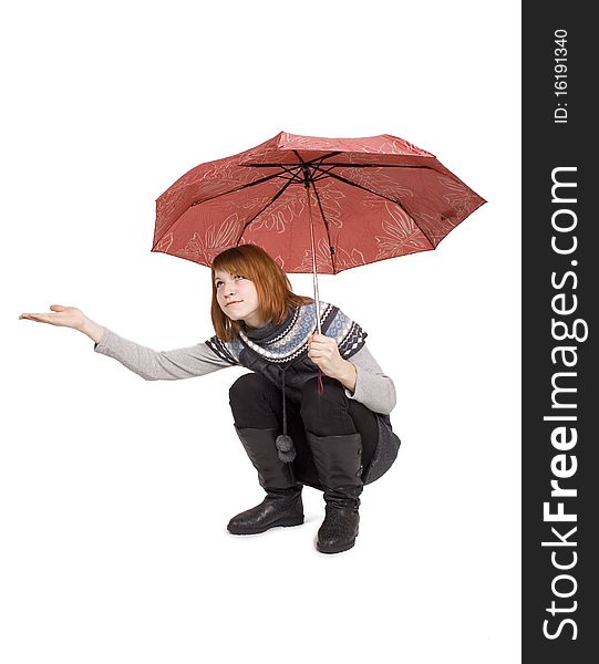 Young beautiful girl in knit dress with red umbrella sitting and stretch out her hand, isolated on white