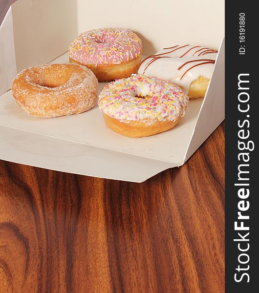 Various doughnuts in a box on an office desk. Various doughnuts in a box on an office desk