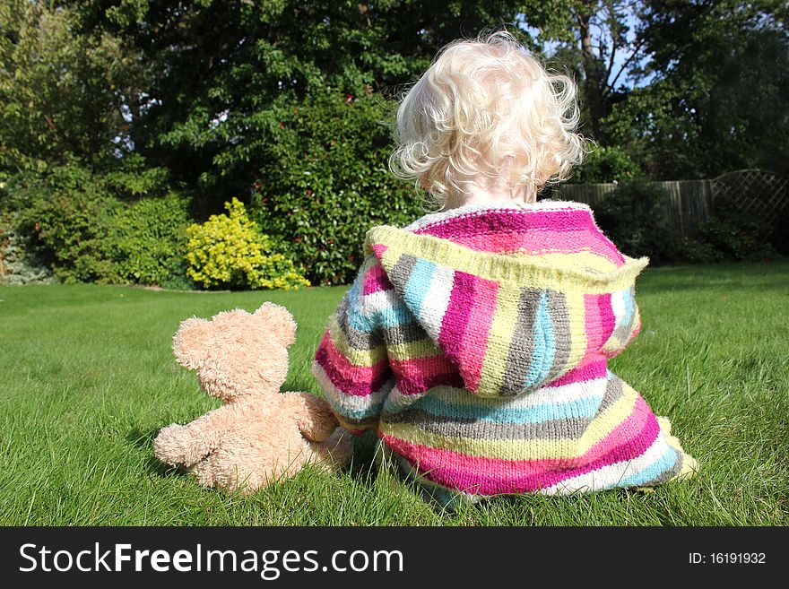 Small girl cuddling teddy in the garden. Small girl cuddling teddy in the garden