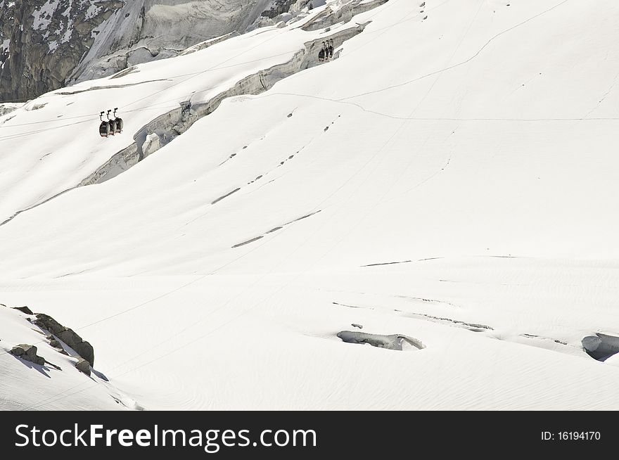 From the summit of l'Aiguille du Midi (3,842 m), the views of the Alps are spectacular. In this picture, you can see the panoramic funicular leading to a peak in Italy. From the summit of l'Aiguille du Midi (3,842 m), the views of the Alps are spectacular. In this picture, you can see the panoramic funicular leading to a peak in Italy