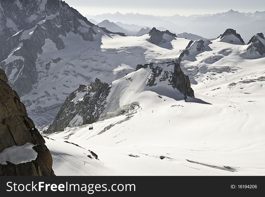 From the summit of l'Aiguille du Midi (3,842 m), the views of the Alps are spectacular. In this picture, you can see the panoramic funicular leading to a peak in Italy. From the summit of l'Aiguille du Midi (3,842 m), the views of the Alps are spectacular. In this picture, you can see the panoramic funicular leading to a peak in Italy