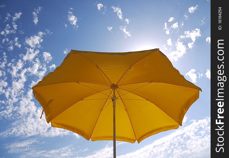 A beach yellow umbrella on the blue sky