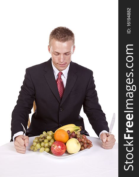 A man sitting at the table getting ready to dig into his plate of fruit while he licks his lips. A man sitting at the table getting ready to dig into his plate of fruit while he licks his lips.
