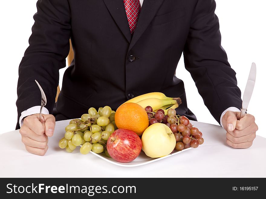 A close up view of a man holding his fork and knife getting ready to dig into a plate of fruit. A close up view of a man holding his fork and knife getting ready to dig into a plate of fruit.