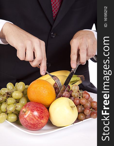 A close up view of a man holding his fork and knife getting ready to dig into a plate of fruit. A close up view of a man holding his fork and knife getting ready to dig into a plate of fruit.