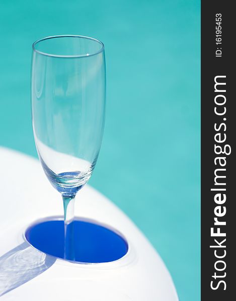 Empty fizz glass in rubber inflatable pool table with azure water in background. Empty fizz glass in rubber inflatable pool table with azure water in background