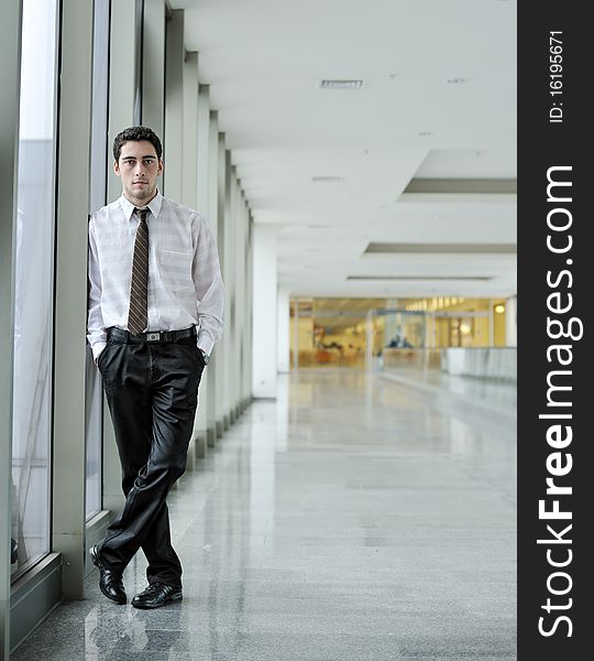 Handsome young man in business suit standing in office environment. Handsome young man in business suit standing in office environment