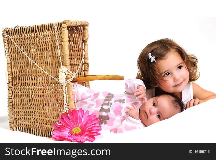 Two sisters playing and smiling in a basket with pink flower