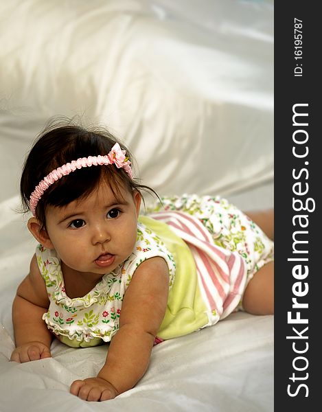 Baby on stomach looking and smiling wearing yellow baby wear. Baby on stomach looking and smiling wearing yellow baby wear