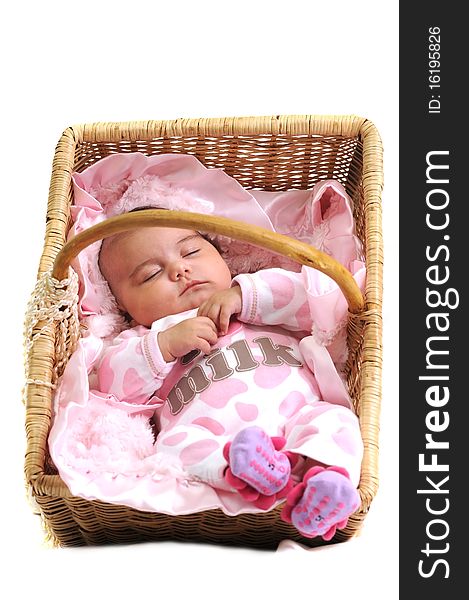 Baby girl in pink dots laying in a brown basket draped with white beads. Baby girl in pink dots laying in a brown basket draped with white beads