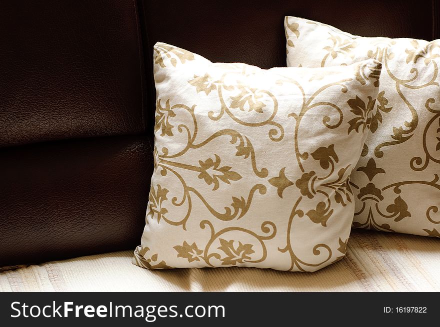 Close up picture of two pillows on a leather sofa