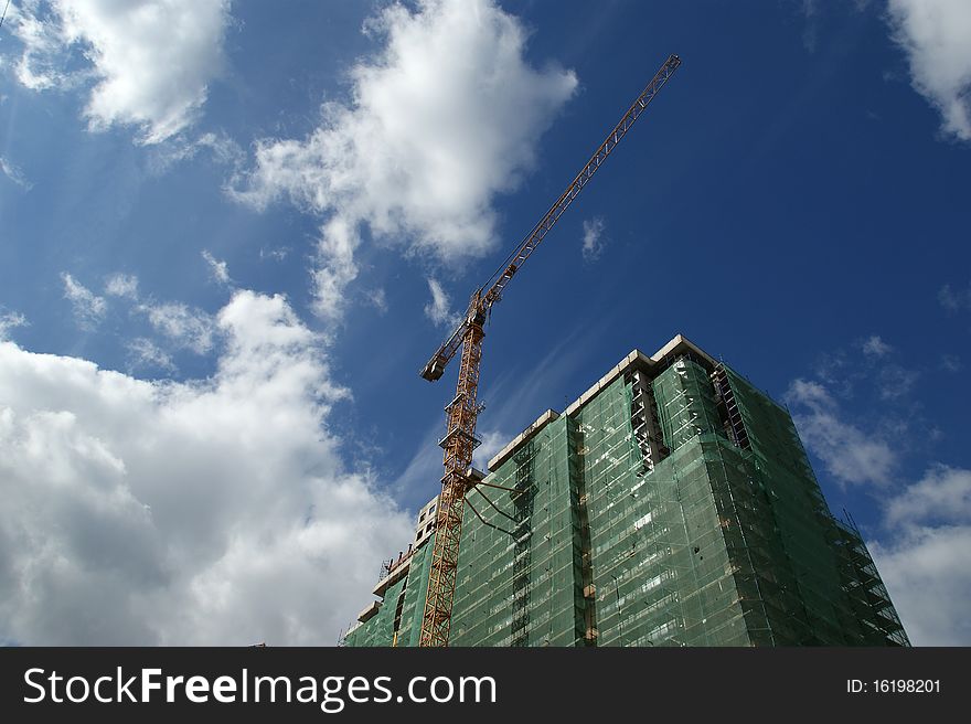 Building crane at the background of a multi-storey building under construction