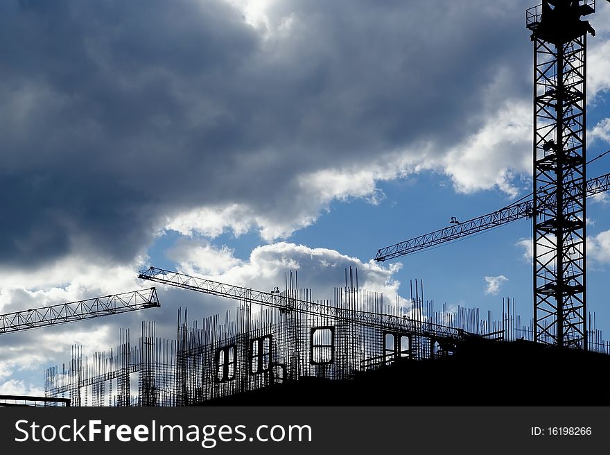 Elevating construction crane against the background of house under construction
