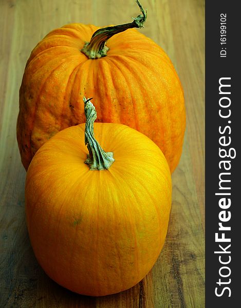 Two pumpkins on a wooden base
