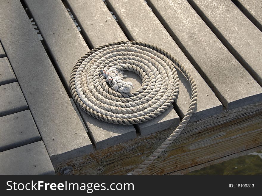 A weathered coiled rope on a sun-bleached dock in the boat marina at Lahaina, Maui. A weathered coiled rope on a sun-bleached dock in the boat marina at Lahaina, Maui.