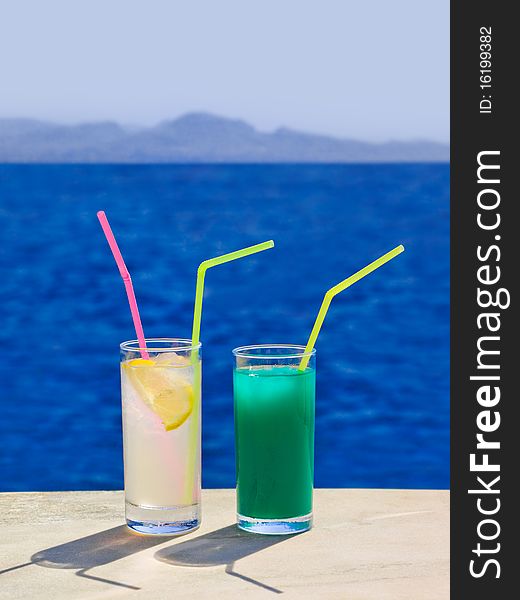 Two cocktails on marble table at beach - travel background