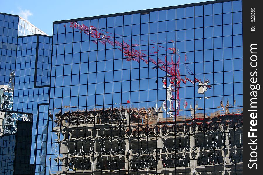 Reflection of construction crane in glass office building