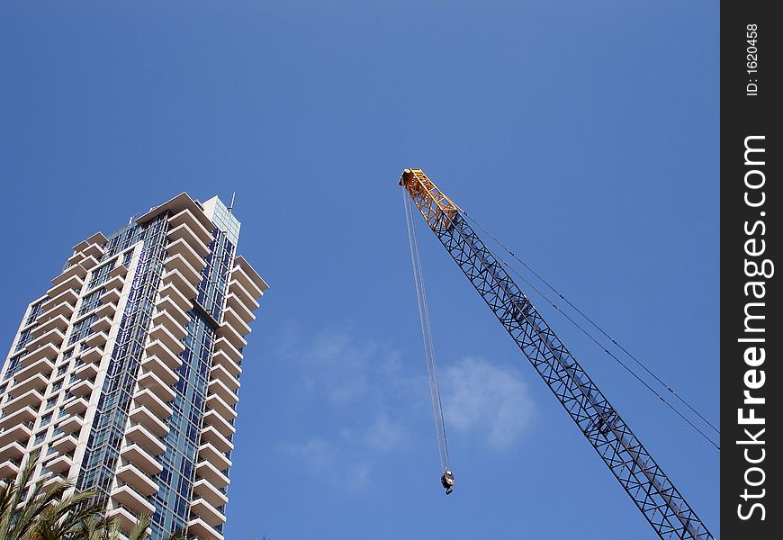 Crane against a blue sky next to a modern building