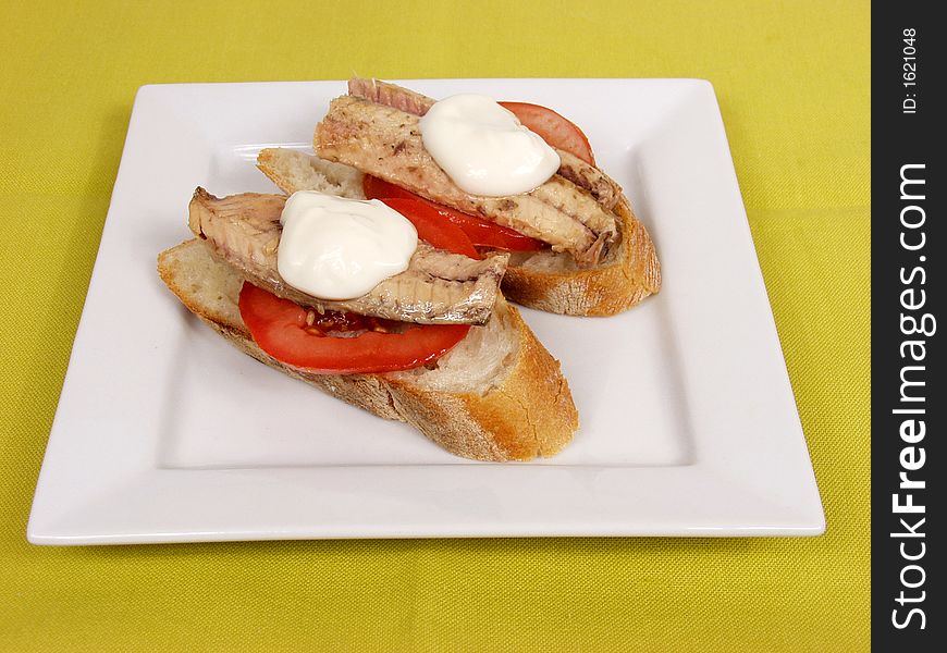 Two pieces of bread with mackerel and mayonnaise on white platter. Two pieces of bread with mackerel and mayonnaise on white platter