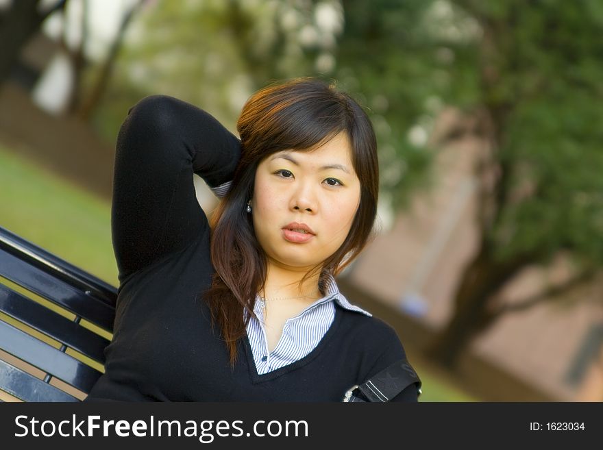 Young asian girl sit on bench and touching her hair. Young asian girl sit on bench and touching her hair