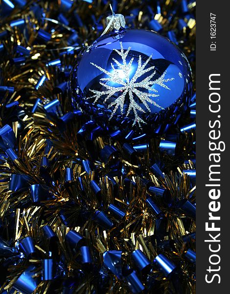 Christmas glass sphere with a pattern on a background of a celebratory tinsel of dark blue color. Christmas glass sphere with a pattern on a background of a celebratory tinsel of dark blue color