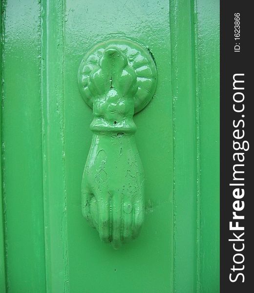 Antique, green painted knocker on old wooden door with same color. Antique, green painted knocker on old wooden door with same color