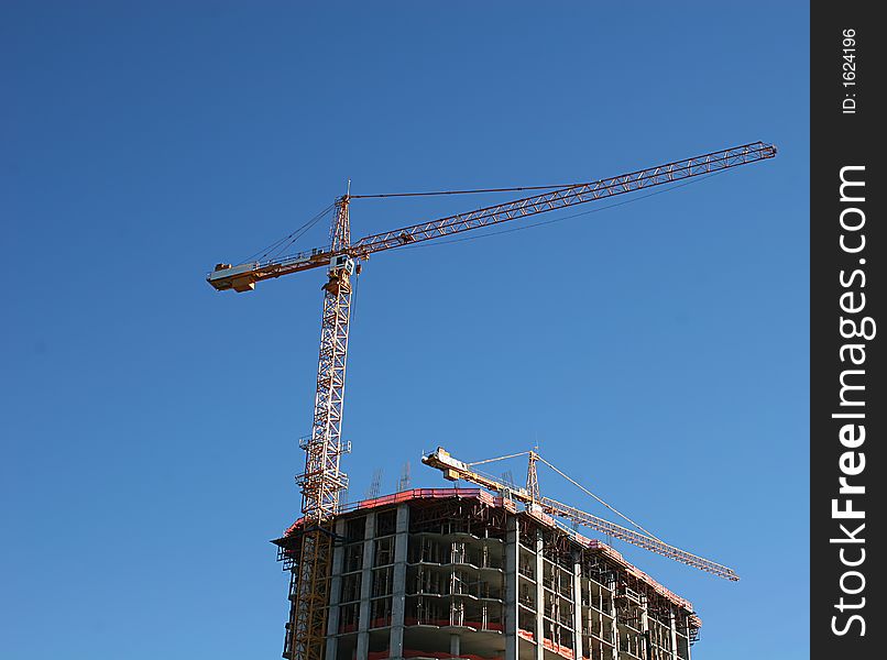 Crane atop Construction tower against blue sky. Crane atop Construction tower against blue sky