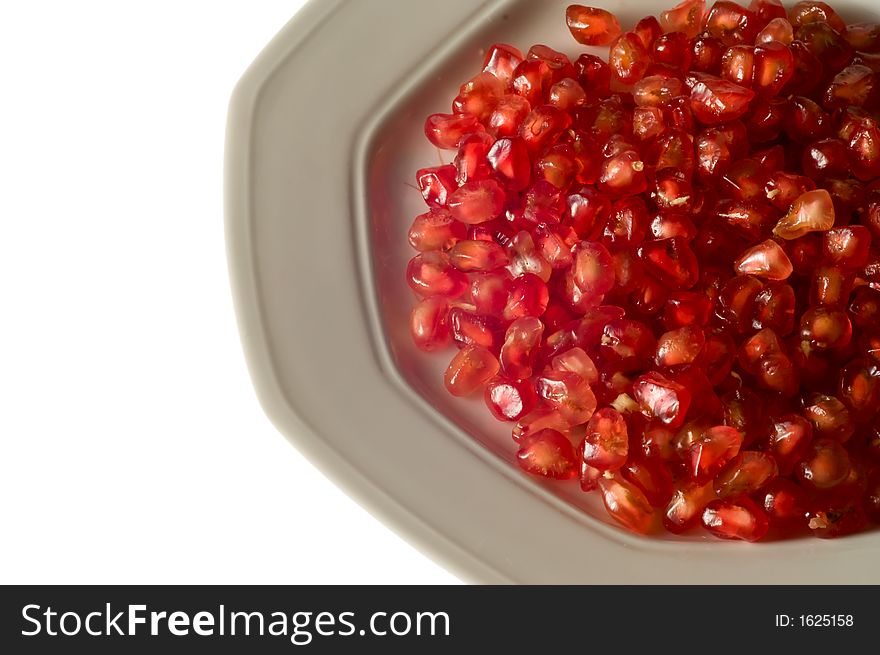 Pomegranate grains on dish isolated on white