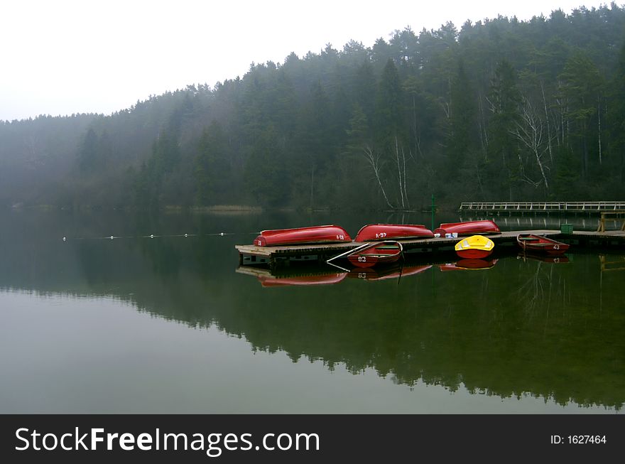 End of the season scenic, boats turned upside-down on the mooring on the still lake. End of the season scenic, boats turned upside-down on the mooring on the still lake