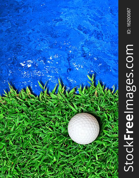 Golf ball on green grass near blue water