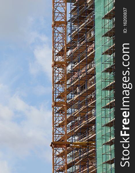 Elevating construction crane against the background of house under construction