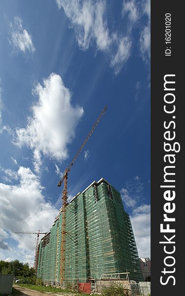 Elevating construction crane against the background of house under construction