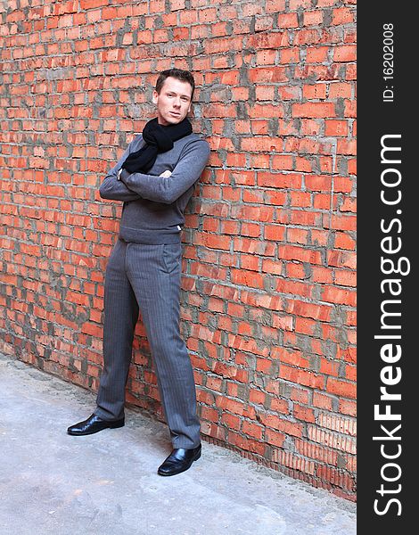 Serious man with hands crossed standing near brick wall. Serious man with hands crossed standing near brick wall.