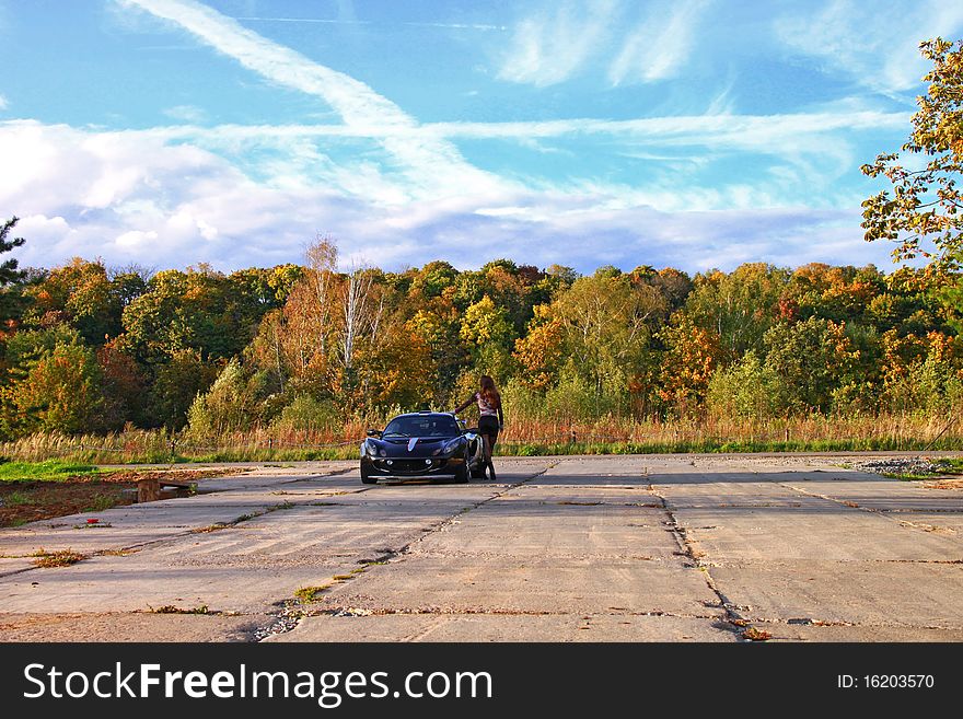 Beautiful girl standing near sport auto under sky